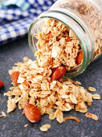 coconut almond granola spilling out of a tipped over mason jar