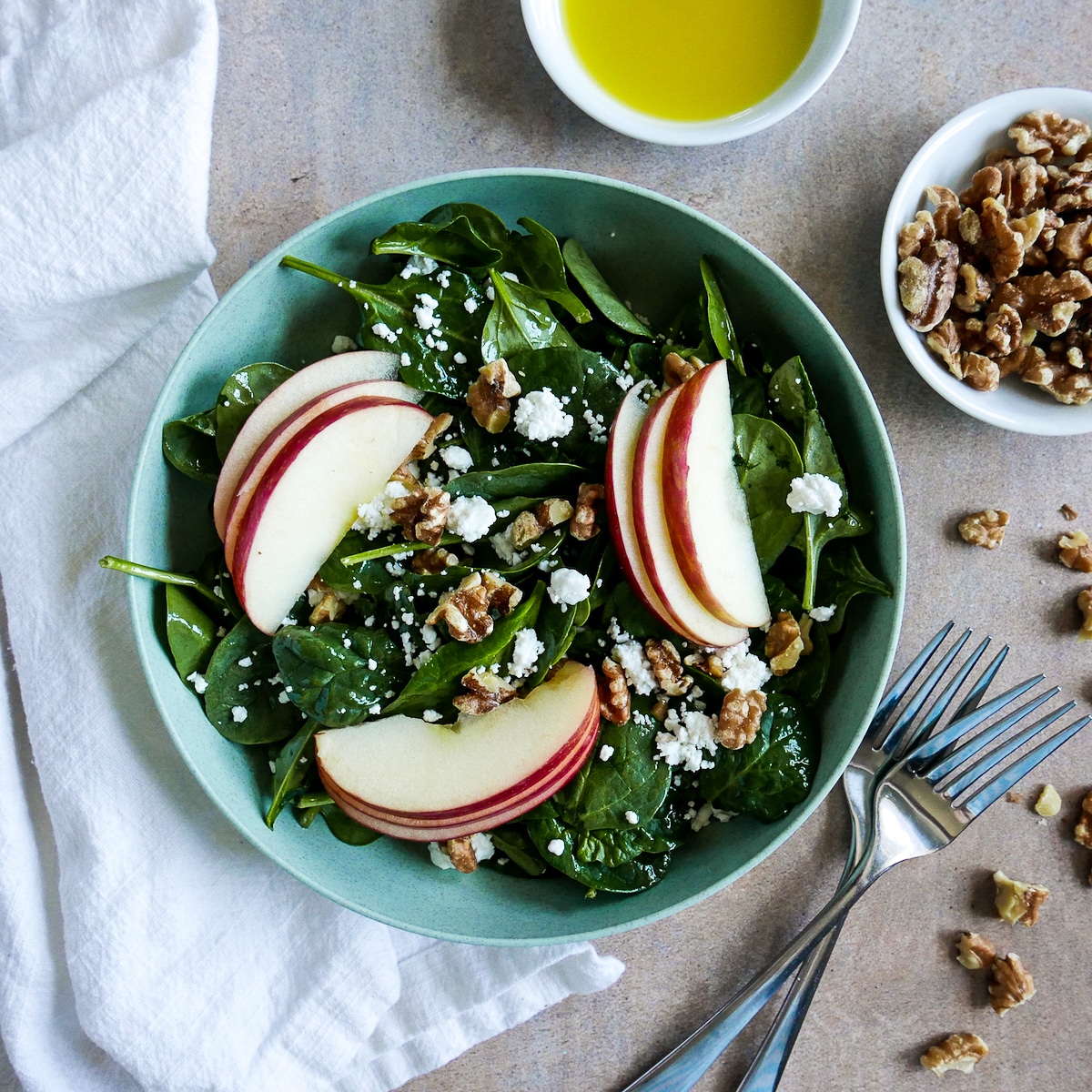 salad-with-goat-cheese-and-walnuts.jpg apple salad with goat cheese and walnuts in a bowl with two forks resting next to it.