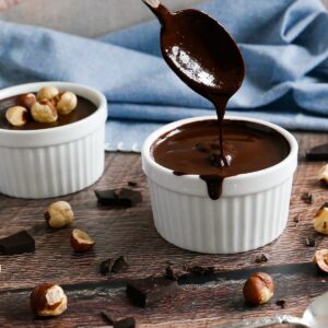 homemade vegan nutella in two white cups with spoon and hazelnuts