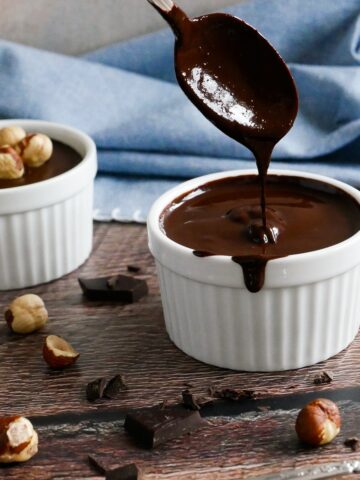 homemade vegan nutella in two white cups with spoon and hazelnuts