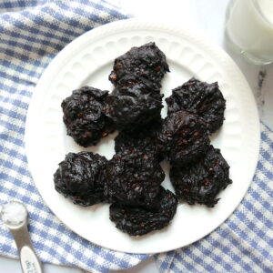 peanut butter fudge cookies arranged on a white plate with a glass of milk next to it and a blue checkered napkin