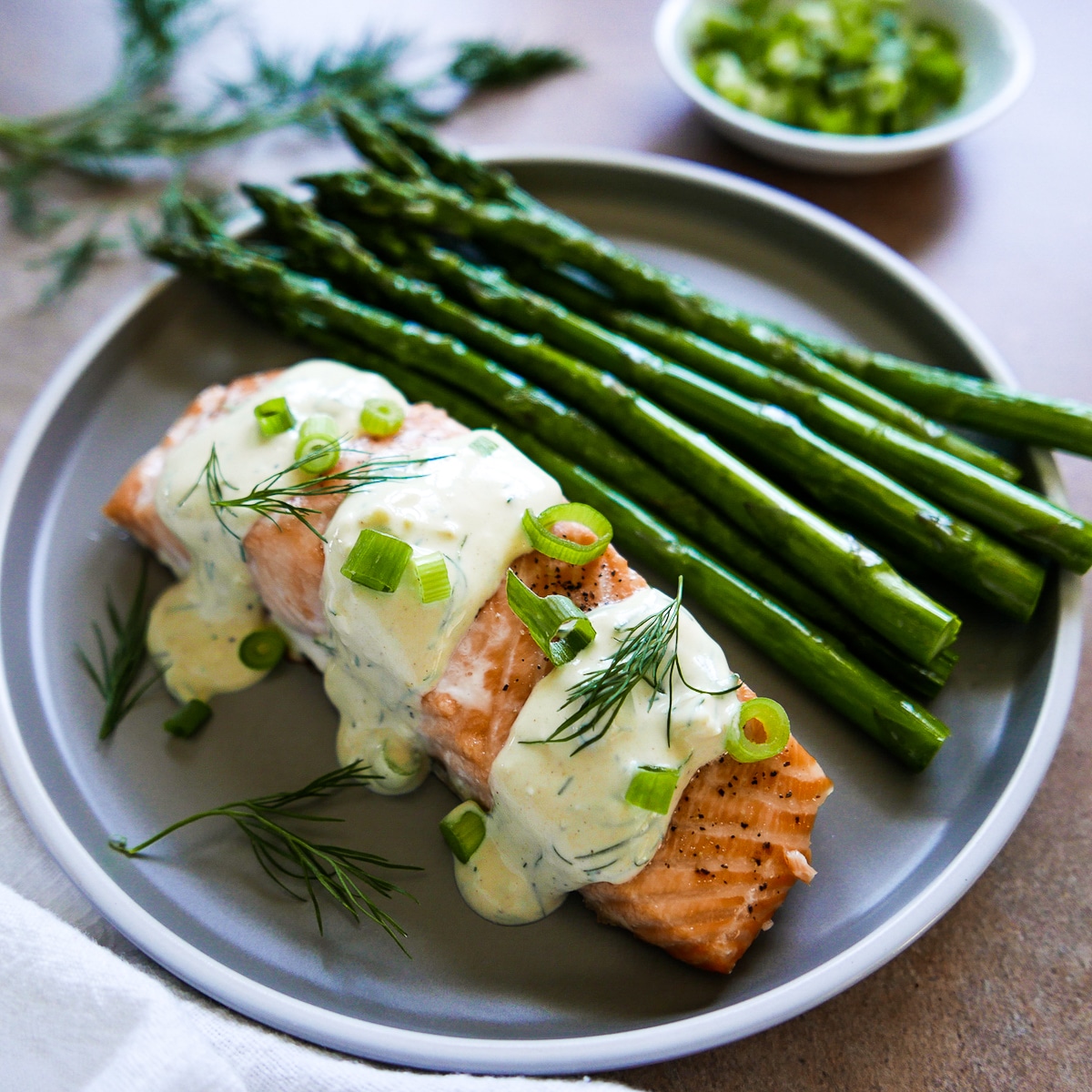 salmon with mustard dill sauce on a plate with roasted asparagus.