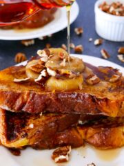 caramelized bananas french toast on a white plate with maple syrup
