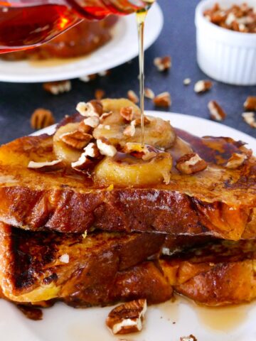 caramelized bananas french toast on a white plate with maple syrup