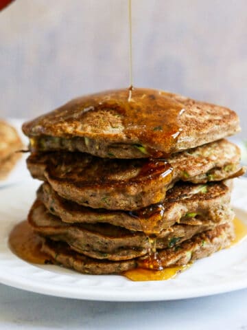 stack of buttermilk pancakes being covered in maple syrup.