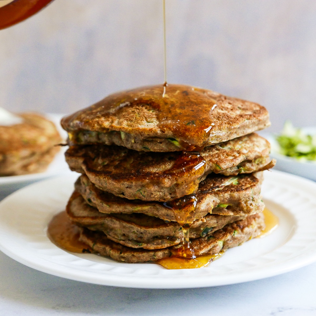 stack of buttermilk pancakes being covered in maple syrup.