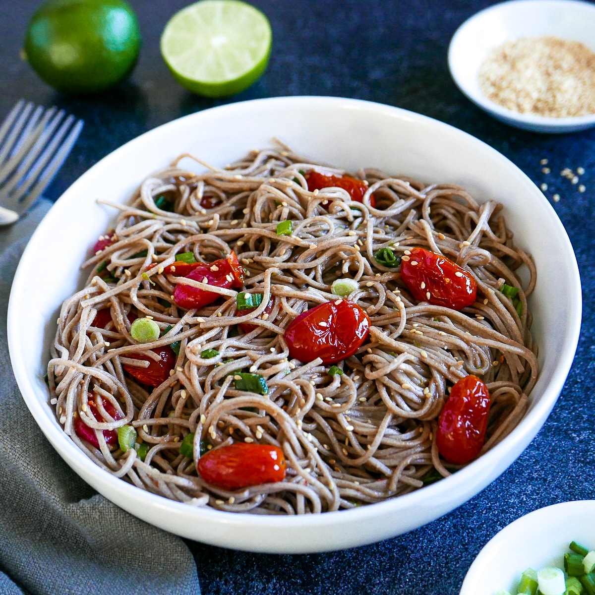 miso noodles with roasted tomatoes in a white bowl with two forks. 