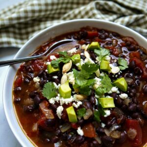 southwest black bean soup with spoon in a white bowl