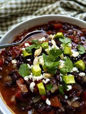 southwest black bean soup with spoon in a white bowl