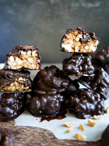 old fashioned peanut butter balls stacked on parchment paper with some cut in half