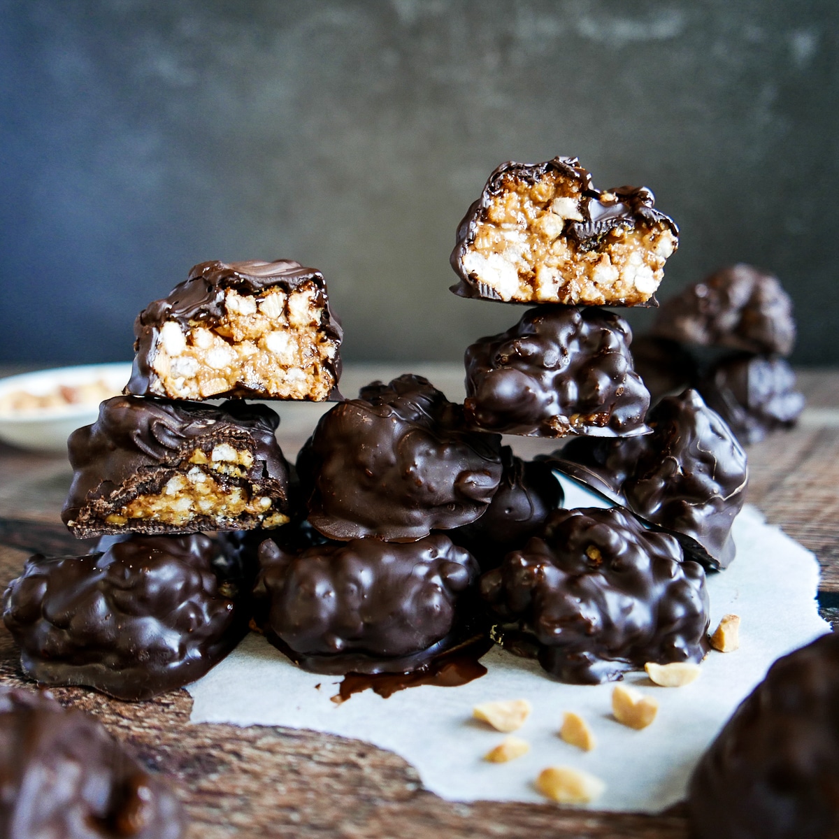 old fashioned peanut butter balls stacked on parchment paper with some cut in half