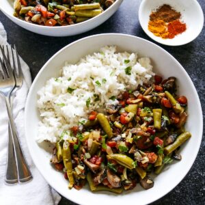 green bean and mushroom curry with white rice and two forks.