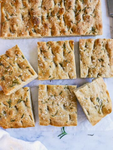 focaccia squares arranged on parchment paper with a knife.