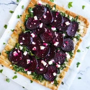 roasted beet tart with feta and kale on parchment paper.