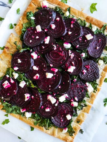 roasted beet tart with feta and kale on parchment paper.