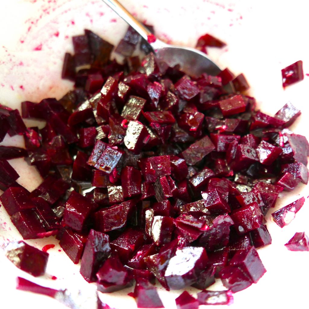 roasted beets in a white bowl with spoon