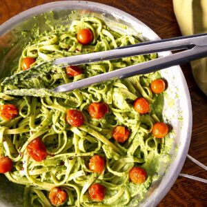 vegan pea pesto pasta in skillet with tongs