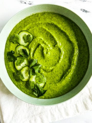 creamy avocado gazpacho in a white bowl.