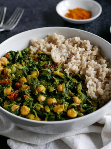 bowl of Indian curry with brown rice and two forks.