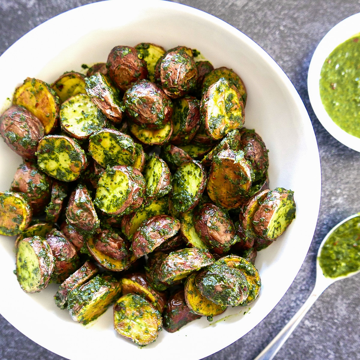 roasted chimichurri potatoes in a white bowl with spoon.
