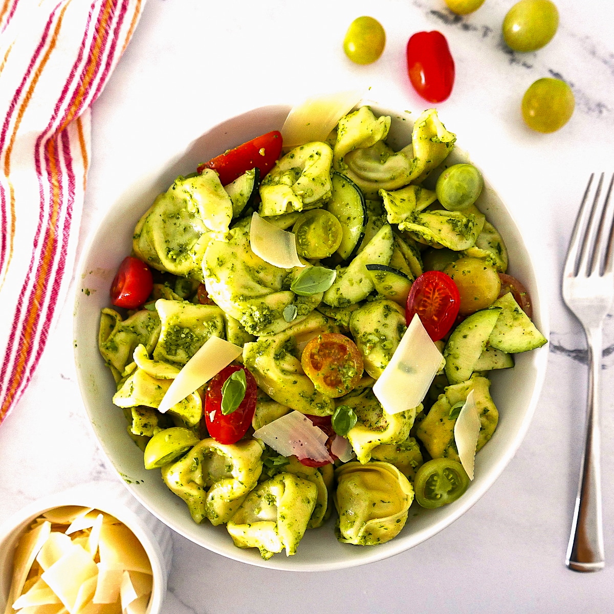 summer-tortellini-salad.jpg Large white bowl of summer tortellini salad with cherry tomatoes and a fork.