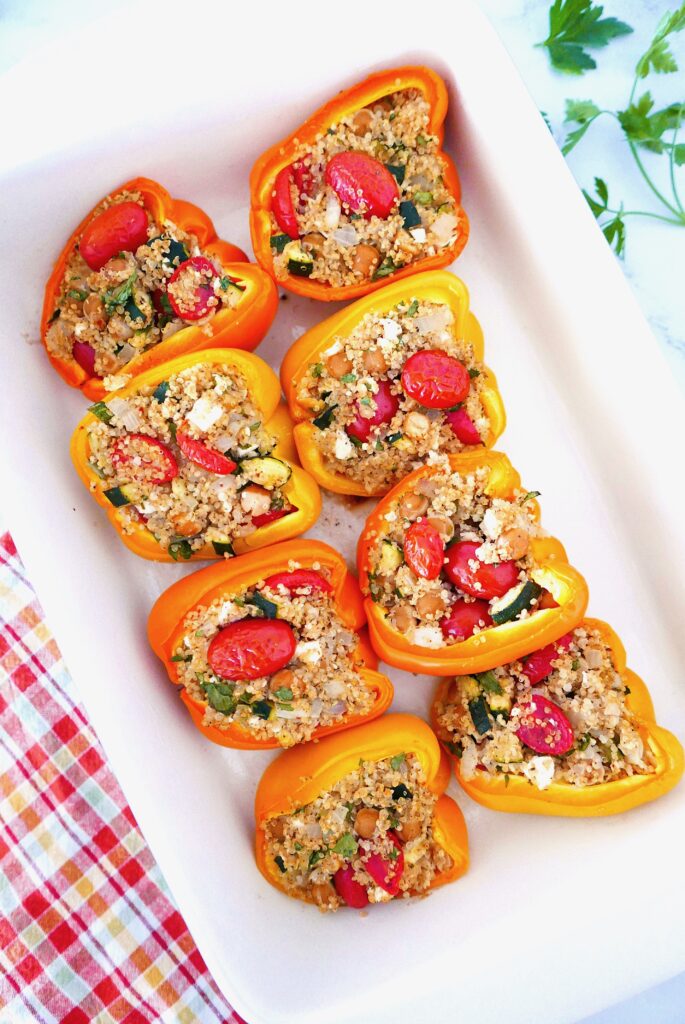 mediterranean stuffed peppers arranged in a casserole dish with cilantro scattered nearby