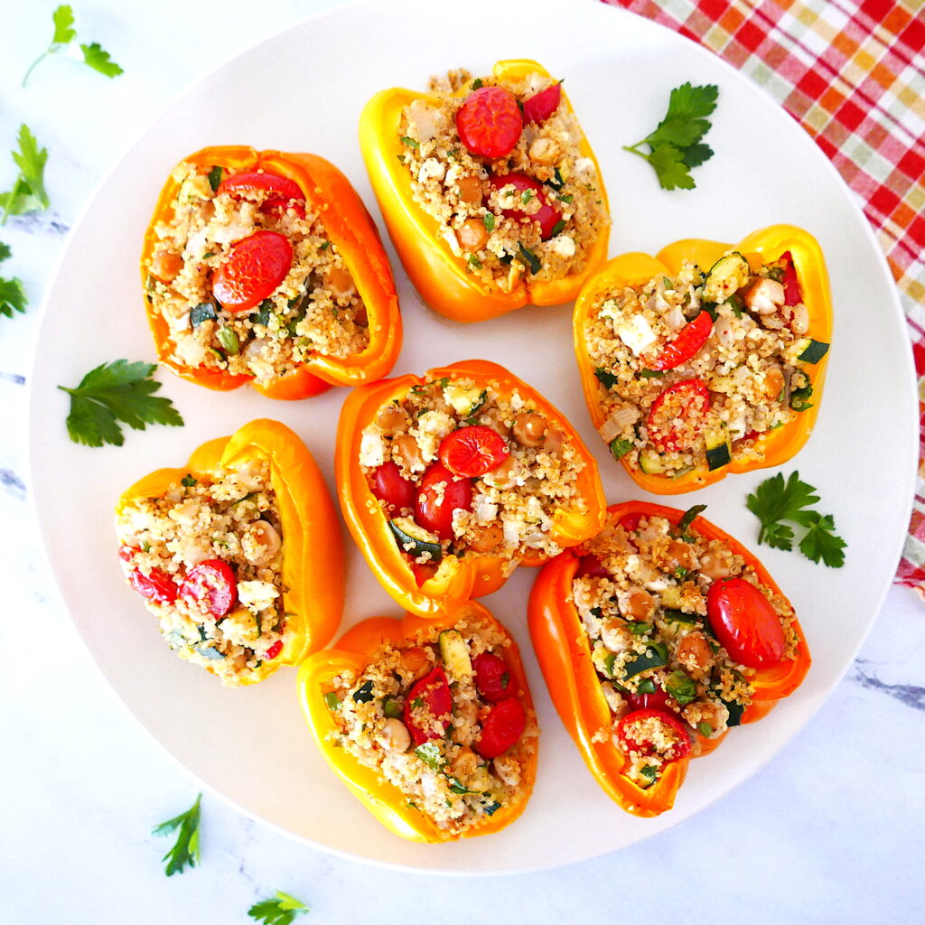 mediterranean stuffed bell peppers arranged on a white plate sitting on a red checkered napkin
