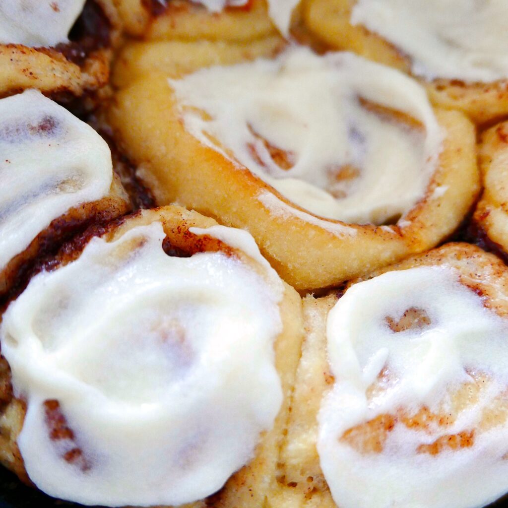 cinnamon buns baked in a baking pan with cream cheese frosting
