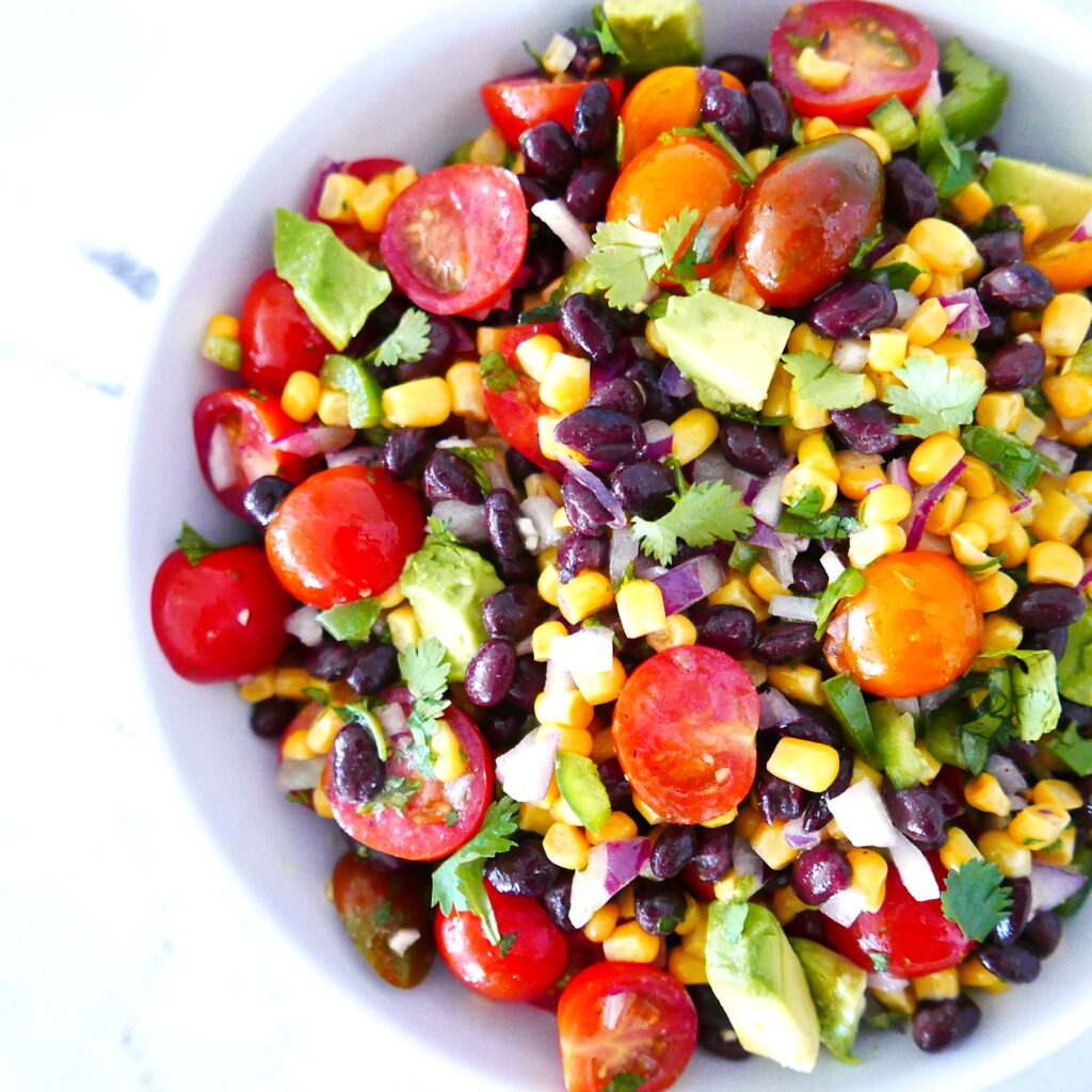 corn avocado black bean salsa in a large white bowl sitting on a marble counter