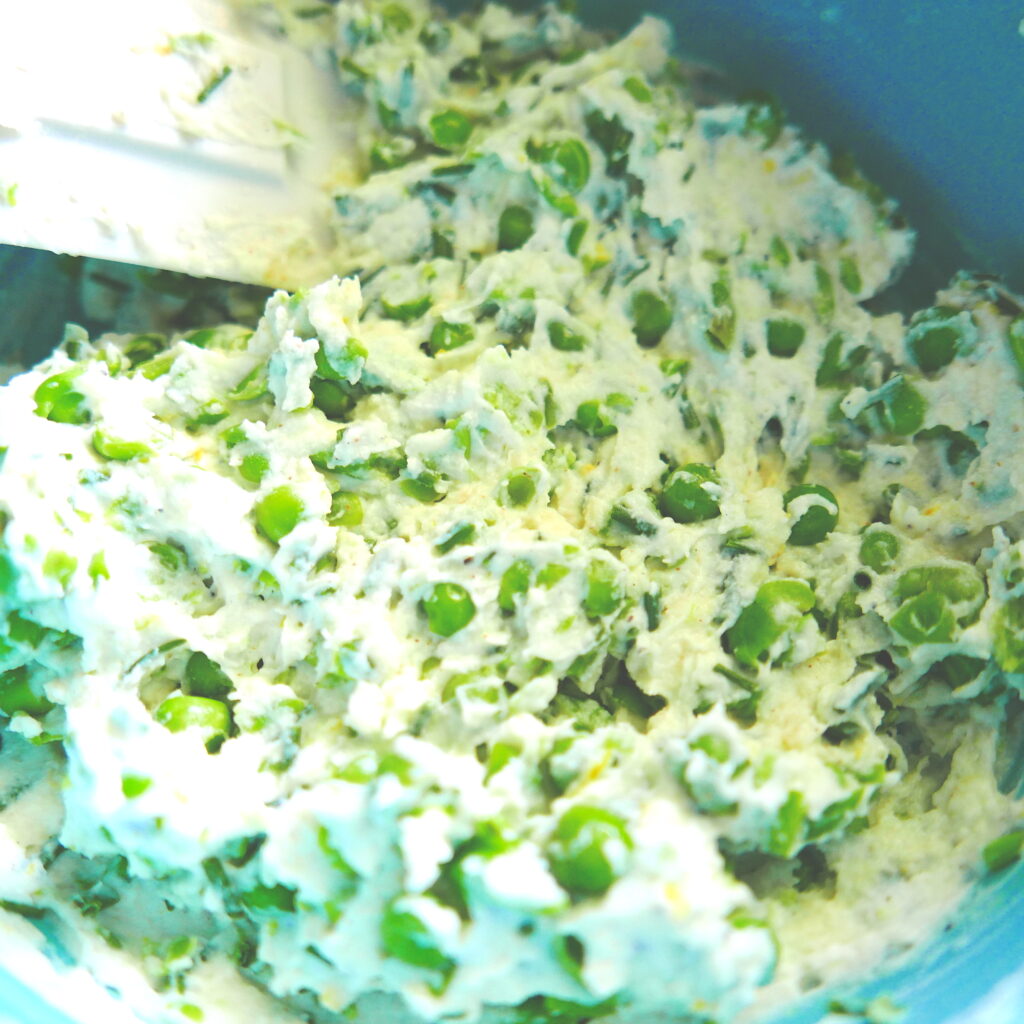 vegetarian pea ravioli recipe being combined in a blue bowl with white rubber spatula