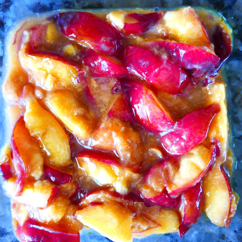 peaches steeped in their juices in a glass baking dish