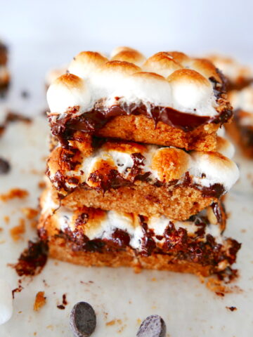 stack of three smores bars with more bars in the background and chocolate chips scattered around