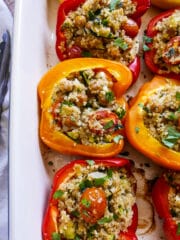 mediterranean stuffed peppers in a baking dish with tongs.