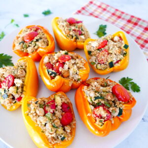 mediterranean stuffed peppers arranged on a white plate with cilantro scattered around plate