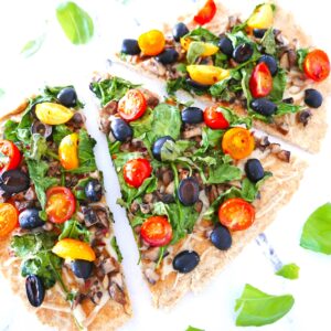 vegan flatbread pizza with lots of veggies arranged on a marble table