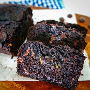 double chocolate zucchini bread sliced on a wooden cutting board with parchment paper.