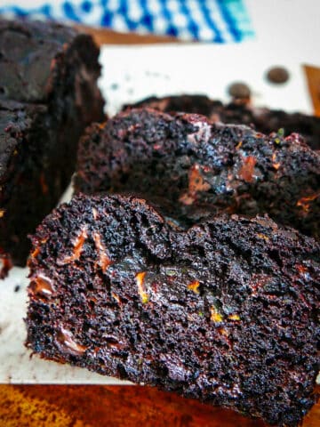 double chocolate zucchini bread sliced on a wooden cutting board with parchment paper.