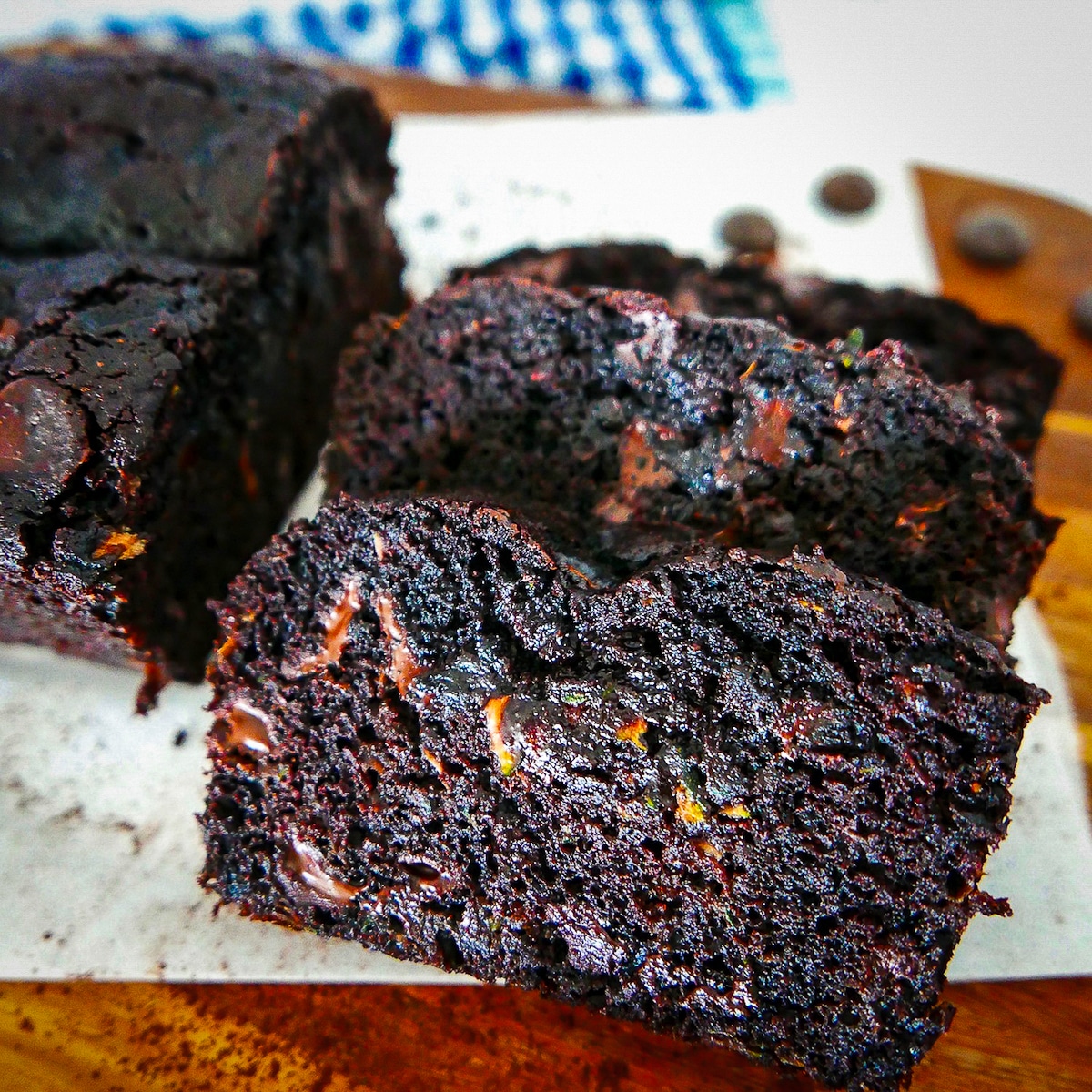 double chocolate zucchini bread sliced on a wooden cutting board with parchment paper.