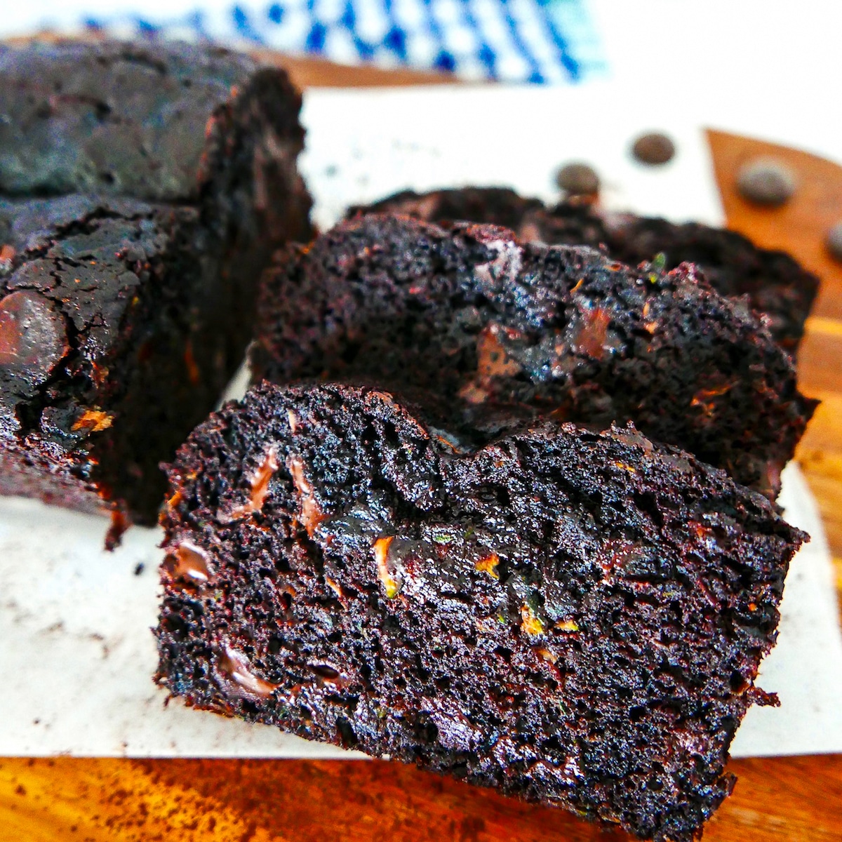 chocolate zucchini bread sliced on a wooden cutting board with parchment paper.