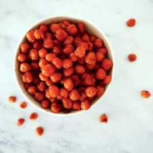 bbq roasted chickpeas in a small bowl with chickpeas scattered around bowl