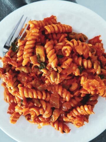 pasta with tomato mascarpone sauce on a white plate with fork