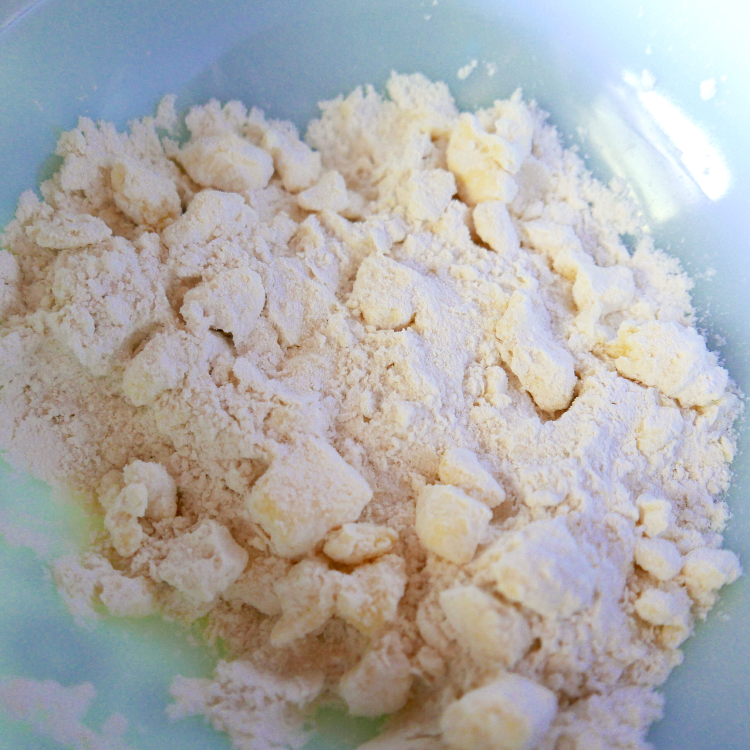 Cubed butter being mixed into gluten free flour in a bowl.