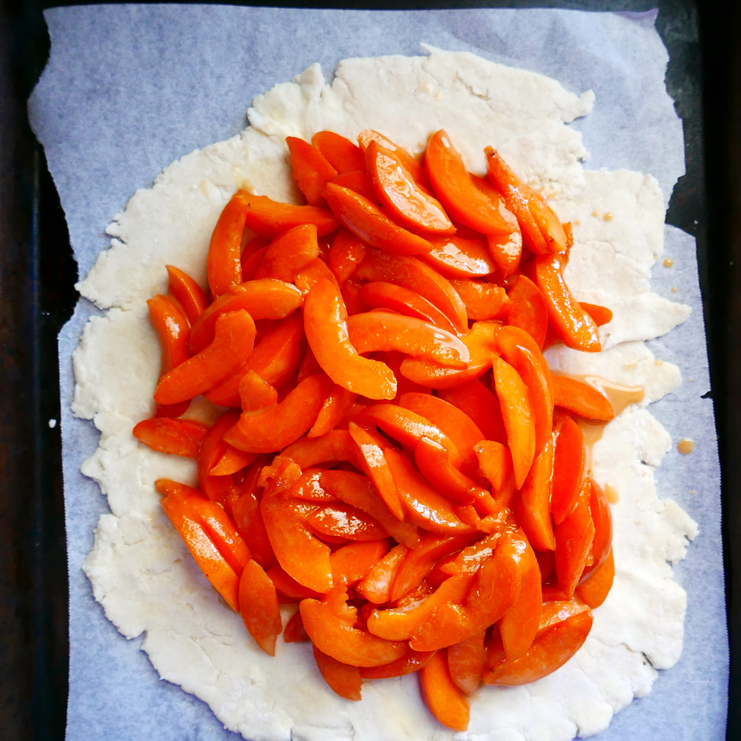 sliced apricots placed on top of galette dough in a circular pattern.