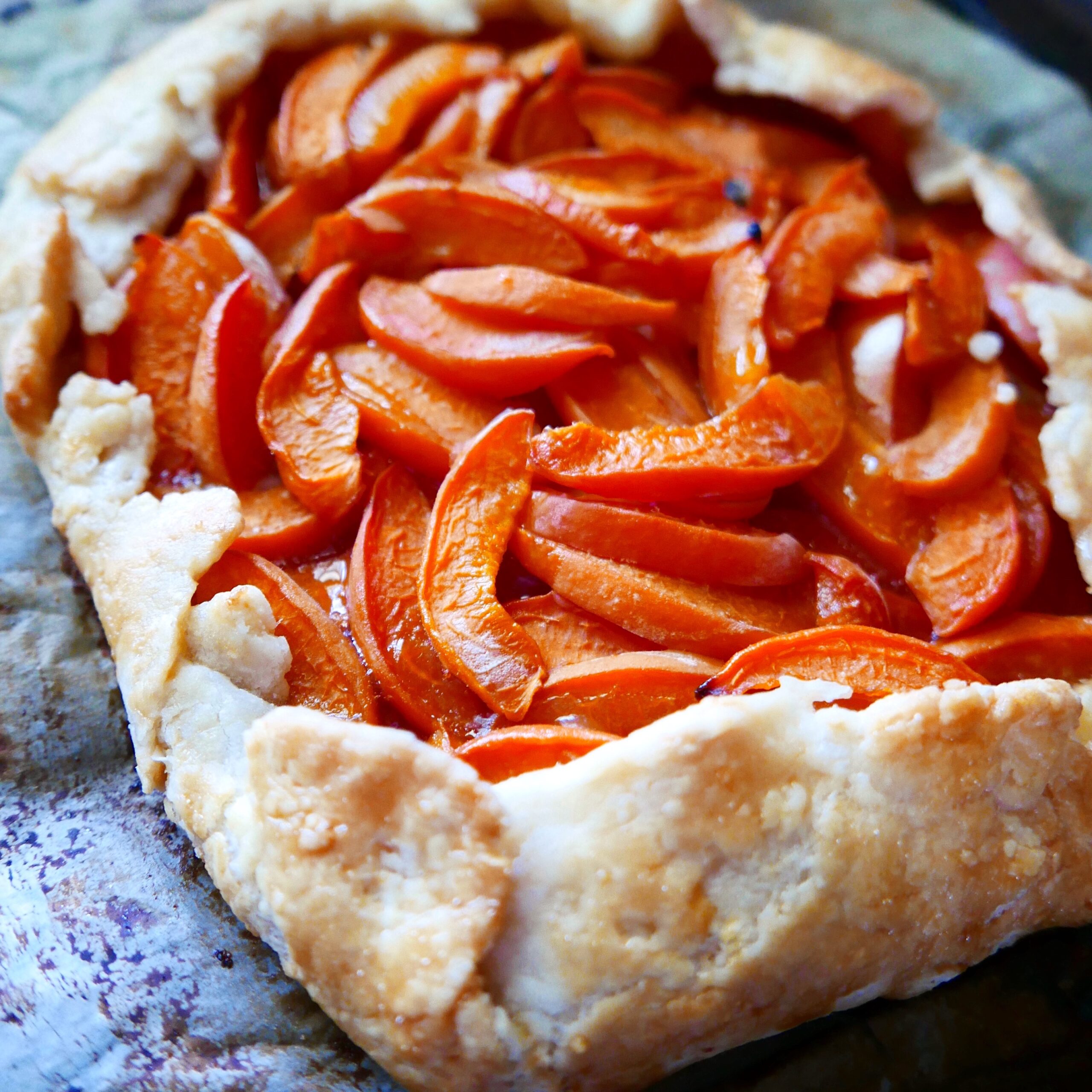 The corner of a galette resting on a parchment paper lined baking sheet.