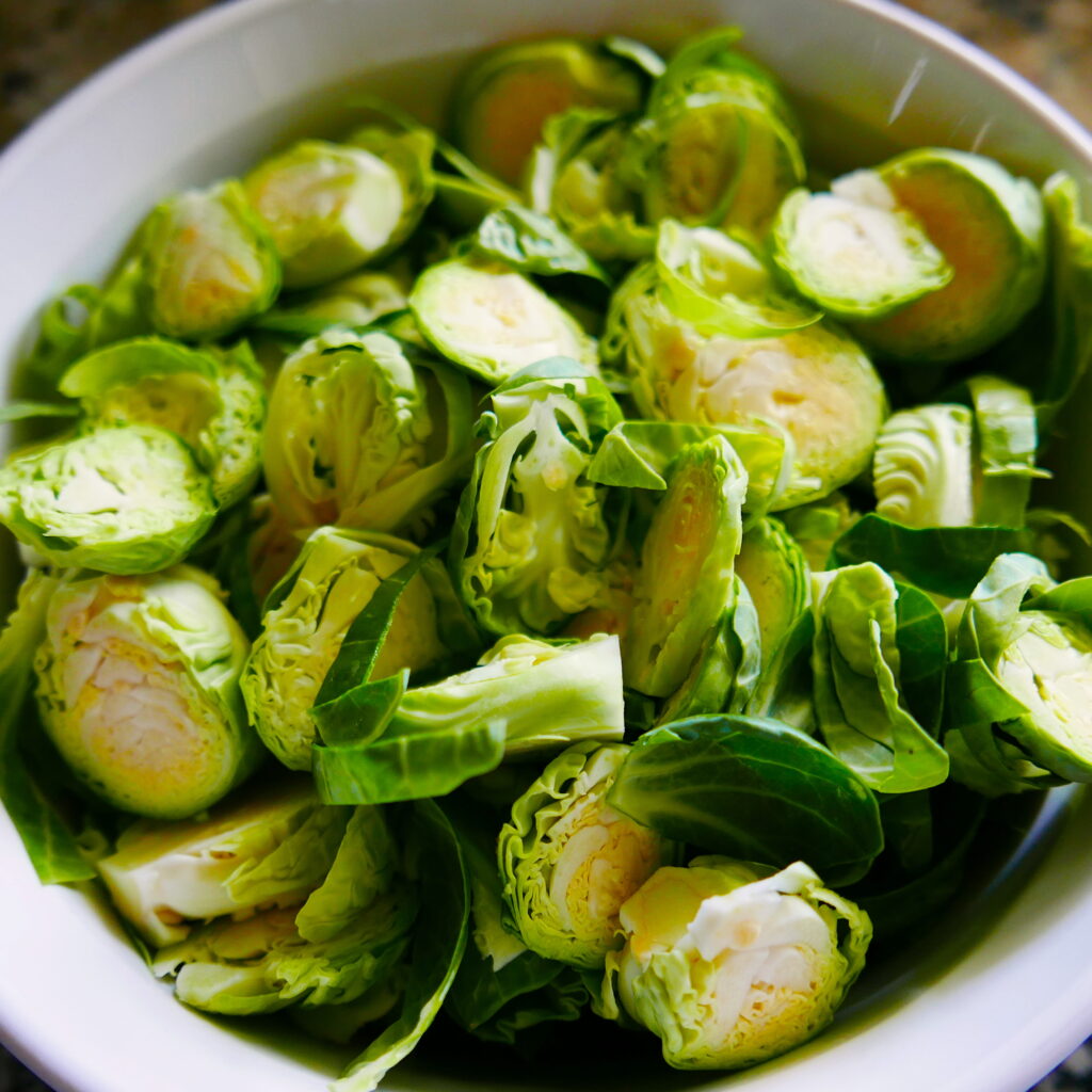 sliced brussels sprouts in a large white mixing bowl