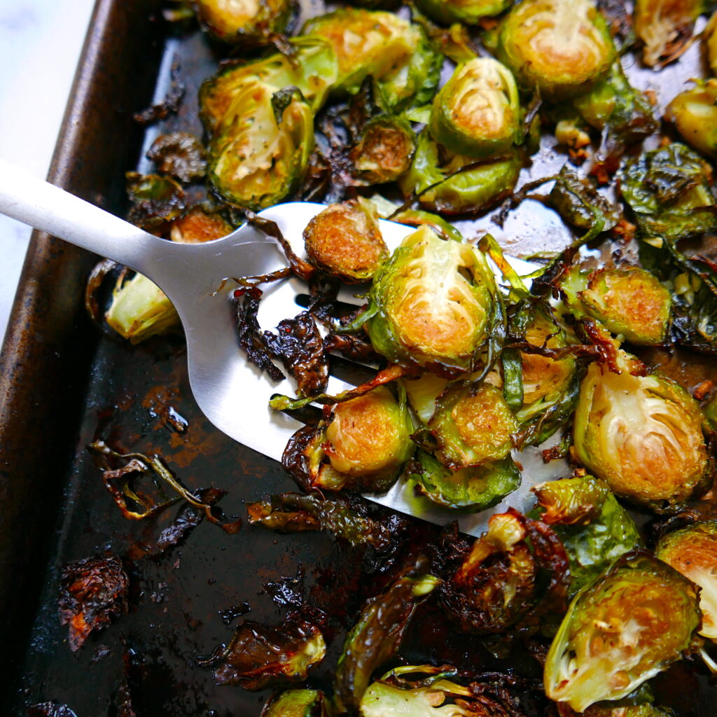 roasted brussel sprouts with garlic on a baking sheet with spatula