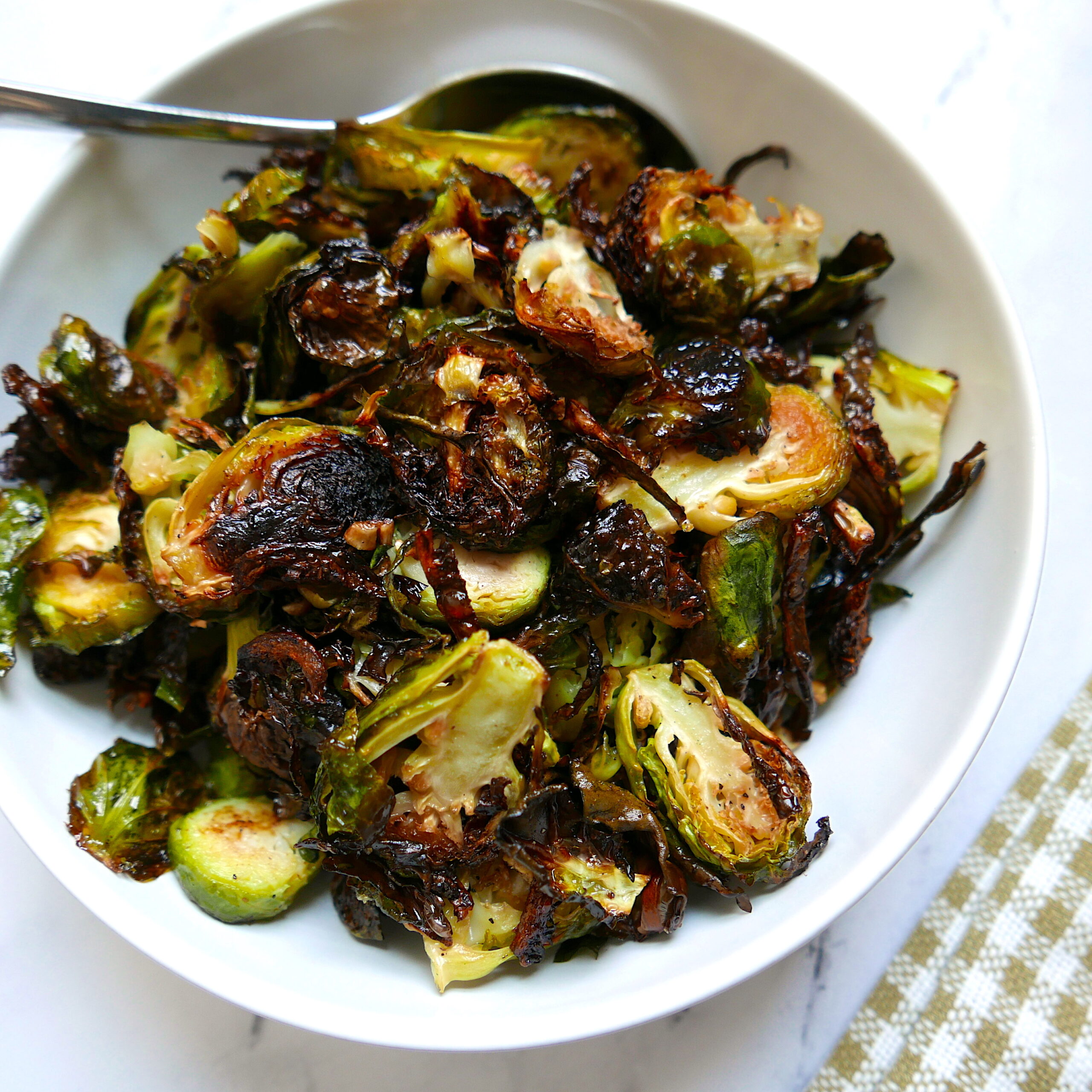 vegan roasted brussel sprouts with garlic in a white bowl with spoon