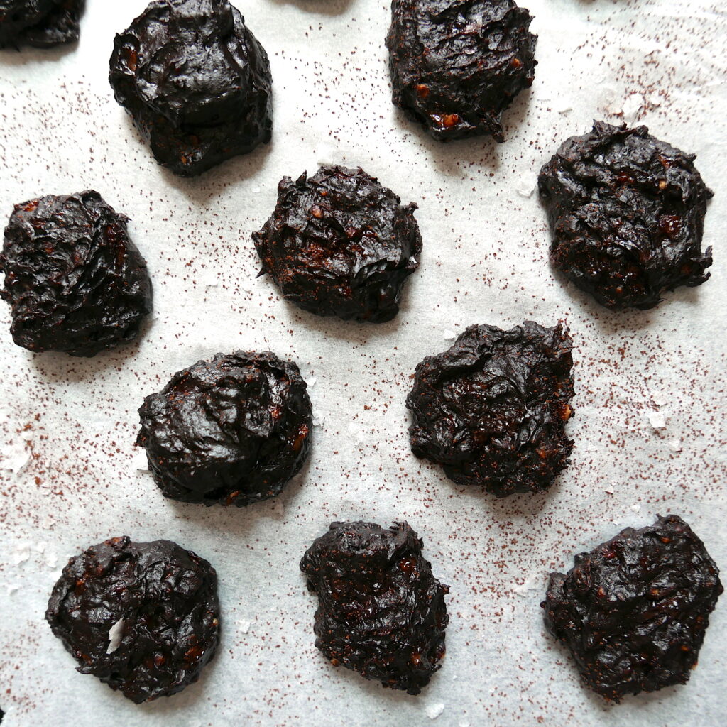 fudgy cookies arranged on a baking sheet with dusted cocoa powder