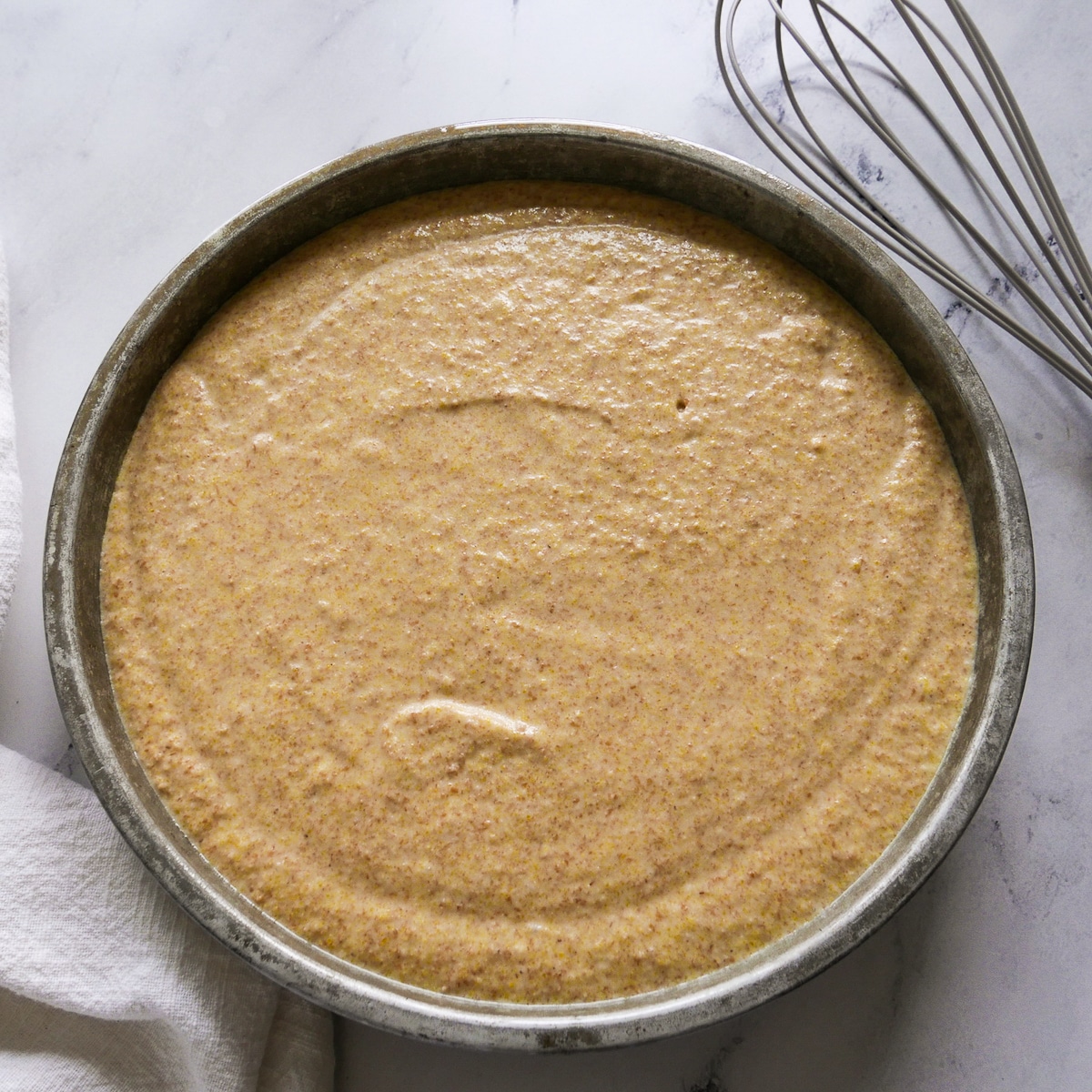 cornbread batter poured into a prepared round cake pan.