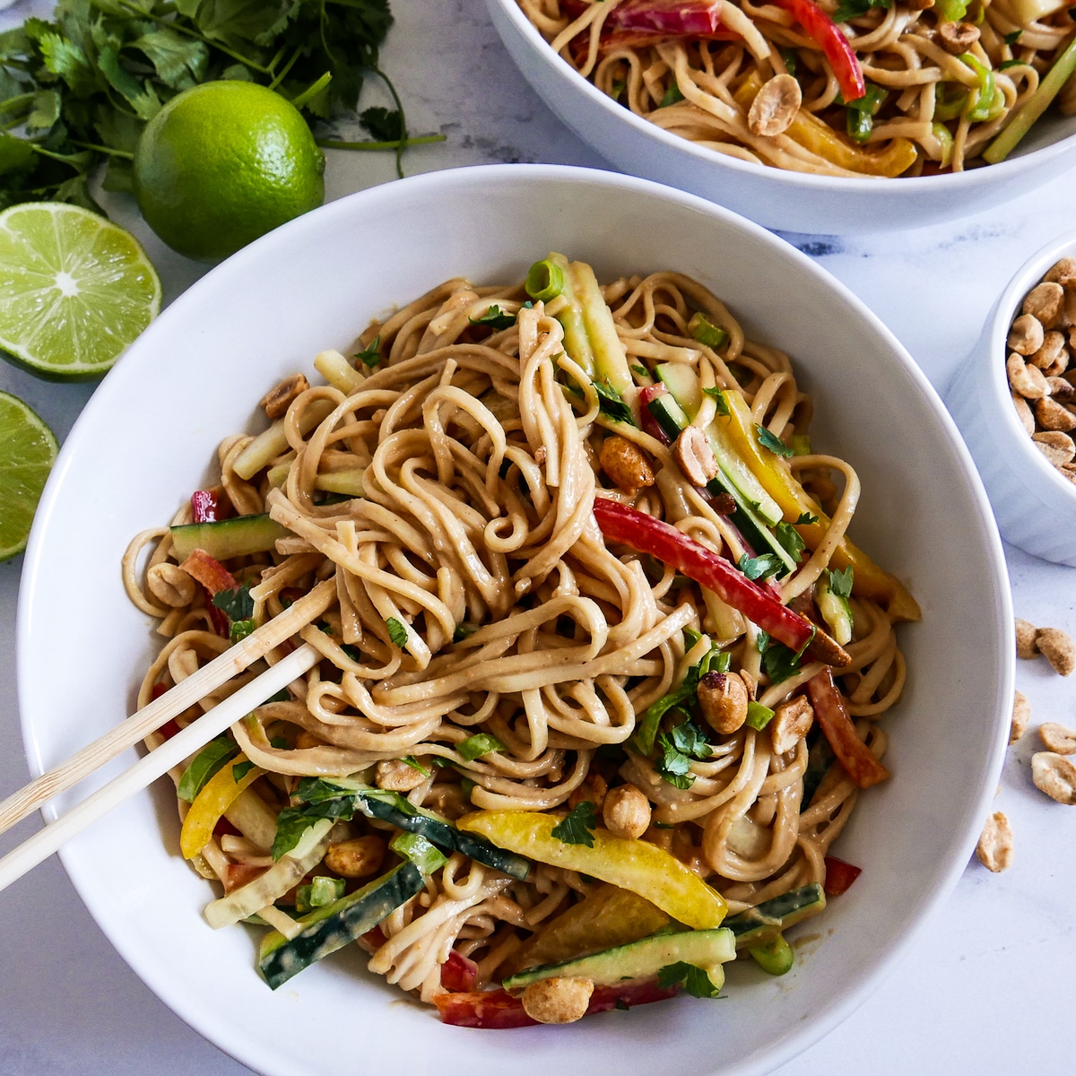 bowl-of-peanut-noodles.jpg white bowl with vegan peanut noodles and a pair of chopsticks.